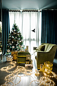 Green living room festively decorated with fairy lights and Christmas tree