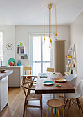 Dining table with wooden top on plexiglas base in bright, white kitchen with yellow accents