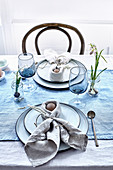 Ei in einer Serviette mit Hasenohren auf gedecktem Tisch in Blau