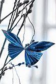 Blauer Schmetterling aus blauem gefaltetem Papier an Weidenzweigen