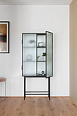 Objets d'art in glass-fronted cabinet with open door