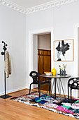 Round black table and designer chairs on multicoloured rug