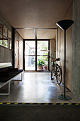 Standard lamp, bicycle and bench in foyer with concrete floor