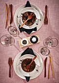 White place settings with coconut shells, chopsticks and wooden cutlery