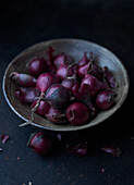 Red onions in a ceramic bowl on a dark surface