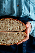 Woman in apron holding slice homemade sourdough bread