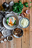 Fried egg on potato on wooden table with fried mushrooms, grated cheese and herbs