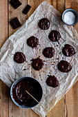 Cook pouring baked tasty cookies with chocolate on baking paper on wooden table