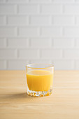 Orangensaft im Glas auf hellem Holztisch