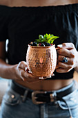 Female carrying metal mug of natural fruit drink with berries and mint leaves