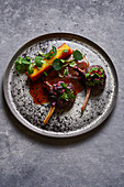 Meat medallions with herbs on plate on gray marble table
