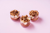 Glass cups with delectable chocolate mousse placed on pink background