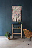 Painted wall hanging above shelves on dark blue wall