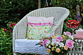 Cushion with hand-sewn cover on wicker armchair in summery garden