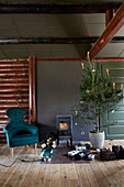 Decorated Christmas tree, gifts and armchair in front of wood-burning stove