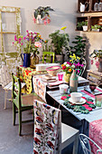 Various tables pushed together to make dining table set with colourful tablecloths and crockery