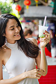Young Asian woman with lod chong (dessert with green tapioca noodles in rice milk)