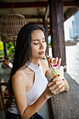 Young Asian woman drinks non-alcoholic pina colada (mocktail) in a bar
