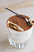 Rraditional coffee flavored dessert tiramisu served in glass cup on table