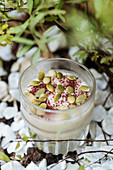 Creamy sweet dessert with cinnamon and seeds in glass cup on decorated surface