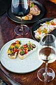 Sandwiches with red yellow sliced cherry tomatoes and herbs on plate with wine