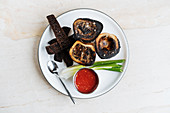 Gegrillte Markknochen mit schwarzen Brotsticks, Chilisauce und Lauchzwiebeln