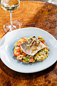 Fillet fish with small square slices of peppers on plate