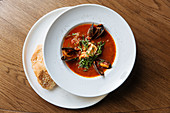Plate with spicy tomato soup, black mussels and seafood with chopped greens