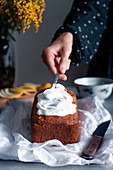 Woman putting whipped cream on cake