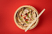 Traditional Chinese steamed dumplings in bamboo steamer with wooden chopsticks
