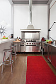 Open-plan stainless steel kitchen with white breakfast bar and steel ceiling in loft apartment