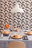 Set dining table in front of wall with grey, black and pink wallpaper with graphic pattern