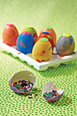 Brightly painted Easter eggs with glitter in eggshell in foreground