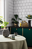Table in kitchen with dark green cupboards and exotic accessories