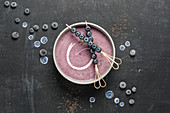A blueberry smoothie bowl with blueberry skewers