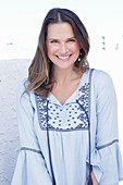 A long-haired woman wearing a blue dress with embroidery detail