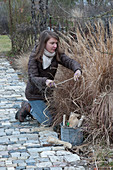 Woman ties grasses together as winter protection