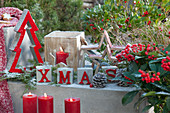 Moderne Weihnachtsdekoration auf der Terrasse mit Buchstaben, Sternen, Tannenbäumchen, Windlicht und Kerzen