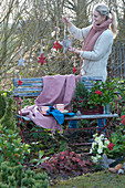 Woman decorates seat in the garden for Christmas with wooden stars