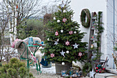 Nordmanntanne geschmückt mit Sternen und Kugeln als Weihnachtsbaum auf der Terrasse, kleine Sitzgruppe, Stühle mit Fell