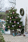 Nordmanntanne geschmückt mit Sternen und Kugeln als Weihnachtsbaum auf der Terrasse