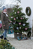 Nordmann fir decorated with stars and balls, woman brings a lantern