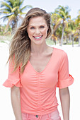 A long-haired woman wearing a short-sleeved salmon-coloured top