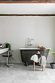 Small, free-standing bathtub in simple bathroom in grey and white