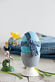Blaues Osterei mit Jeansband im Eierbecher