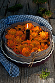 Brennende Kerzen und Ringelblumenblüten in Tarteform mit Filz umwickelt