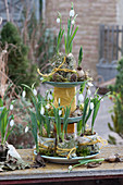 Self-made cake stand made of plates and thread spools with snowdrops in bark