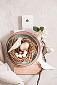 Osterdeko: Osternest dekoriert mit Blütenzweig und selbstgebastelten Papiervögeln
