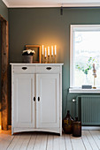 Candlesticks and flower pot on top of white cabinet