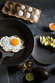 A fried egg in a pan served with fresh avocado for breakfast